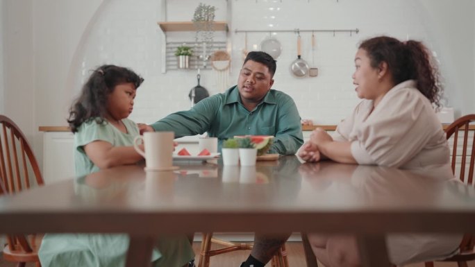 休闲用餐的快乐:亚洲家庭在西瓜上建立联系，在家庭餐桌上创造快乐的时刻。