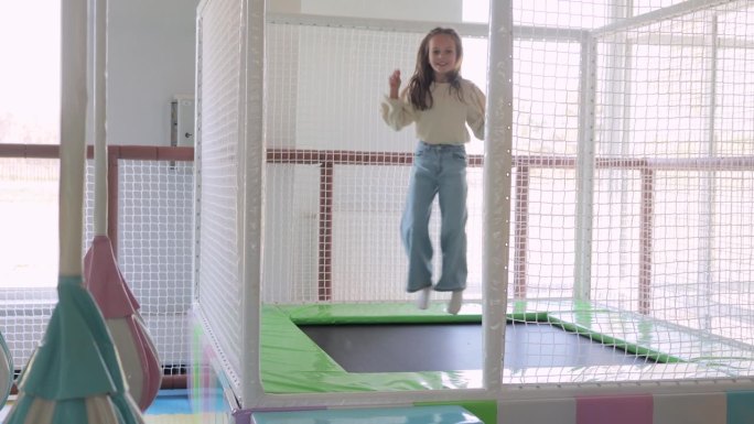 可爱的小女孩在儿童游戏室的蹦床上蹦蹦跳跳，在娱乐中心度过了一段有趣的积极时光。