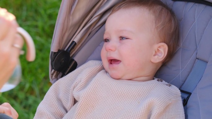 一个可爱的小孩坐在婴儿车里调皮地哭。消极情绪，不服从和歇斯底里的概念。