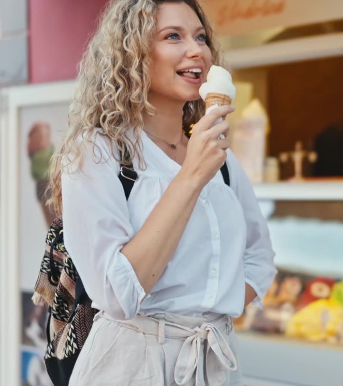快乐的年轻女子在Ptuj - VERTICAL镇的商店外吃冰淇淋蛋筒
