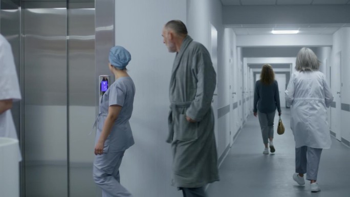 护士和病人走过走廊，过来扶电梯