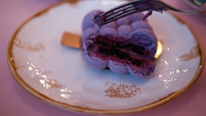 吃一口慕斯蛋糕。吃美味甜美的紫色甜点。餐厅、咖啡馆的糕点。切奶油纹理近距离。吃芝士蛋糕的人。叉子掰断