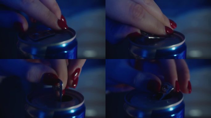 特写:红指甲的女人如何打开一个蓝色的罐装能量饮料
