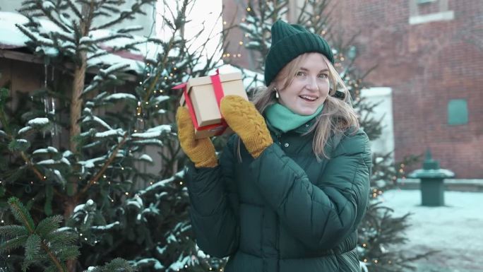 在圣诞购物市场里，一个快乐的年轻美女手里拿着纸制礼盒。寒假特卖。