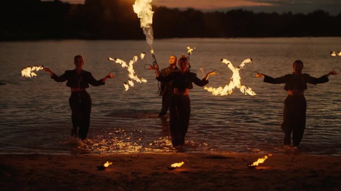 湖岸江畔艺术表演中的火与水，年轻苗条的女子在表演