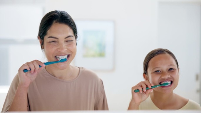 快乐的妈妈，和女孩一起在浴室刷牙进行牙齿保健，卫生或早上在家里例行公事。妈妈和小孩微笑清洁口腔、牙龈