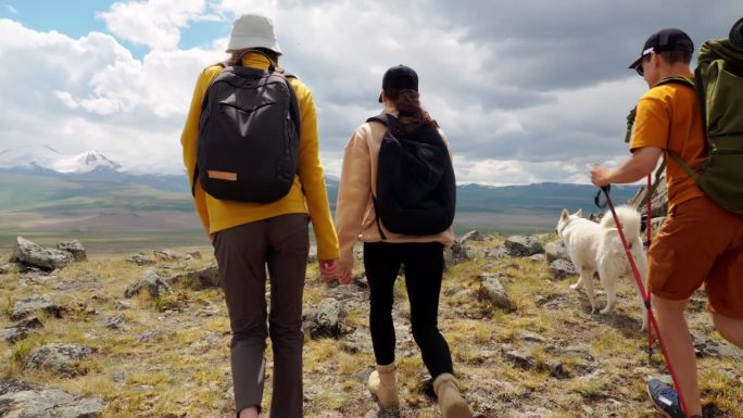 三个徒步旅行者高举双臂，站在高山之巅，喜悦地取得了成功