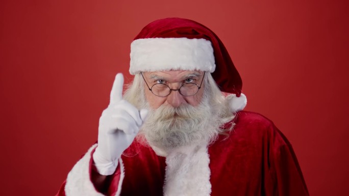 严厉的圣诞老人摇手指，纯红色背景