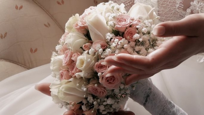 新娘手持一束粉色和白色的玫瑰