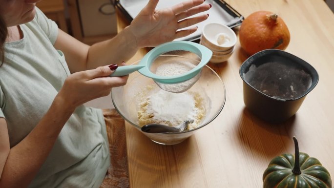 自制南瓜饼干食谱。女人筛面粉，做面团。