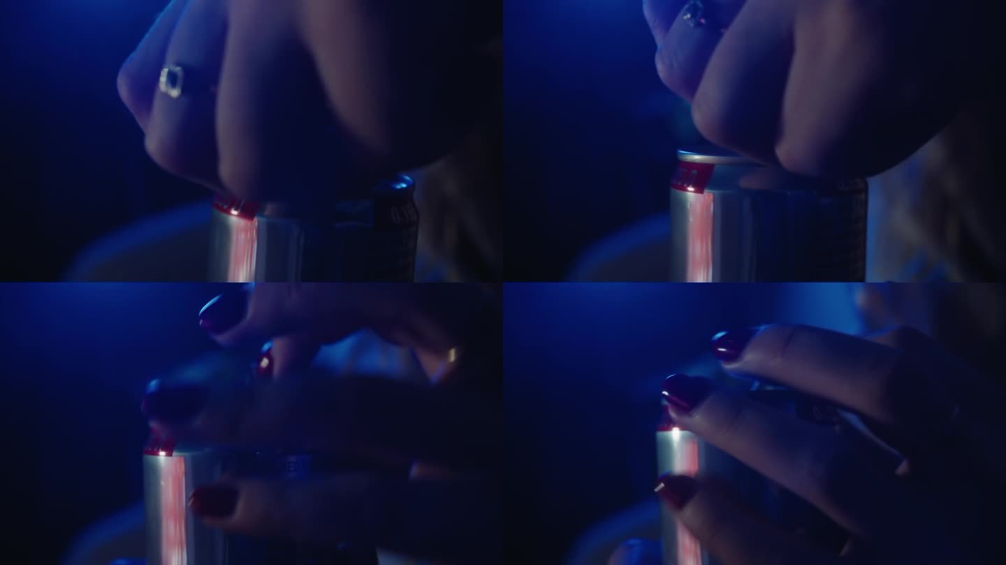 女性手的特写，红指甲打开蓝色的能量饮料罐头