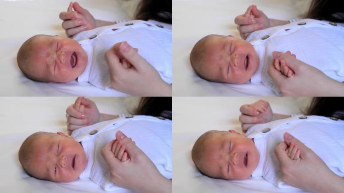 一个啼哭的新生婴儿的画像。一位年轻的母亲抱着婴儿的手臂，对他说话，安慰他。