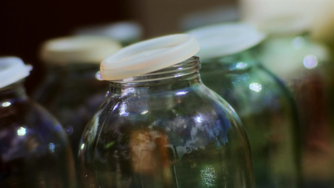 有塑料盖的空玻璃瓶等着苹果汁