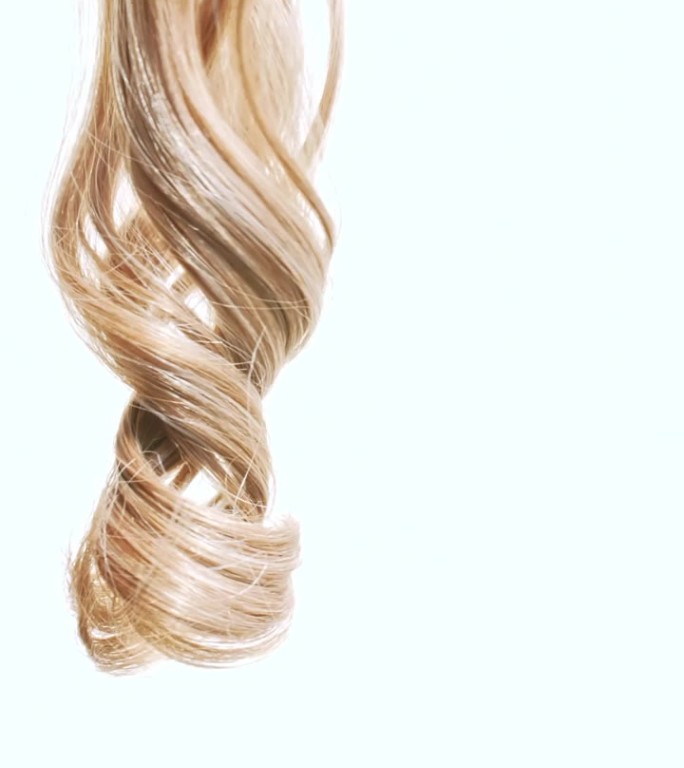 一束束金色的、有光泽的、波浪状的头发。缓慢的运动。护发美容美发。天然化妆品。发色盘