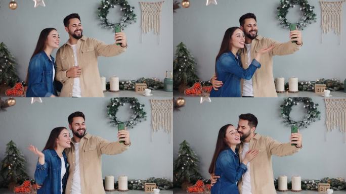 一对恩爱的夫妇用智能手机进行节日视频通话，向朋友和远方的家人致以圣诞快乐的祝福。丈夫拥抱着妻子，快乐