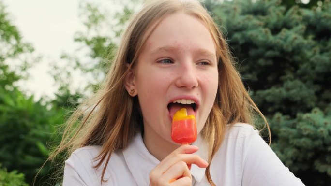 快乐的女孩在绿色夏日公园吃水果冰淇淋