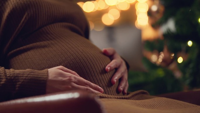 一个怀孕的女人和她的宝宝度过她的第一个圣诞节，年轻的准妈妈抱着怀孕的肚子里的孩子