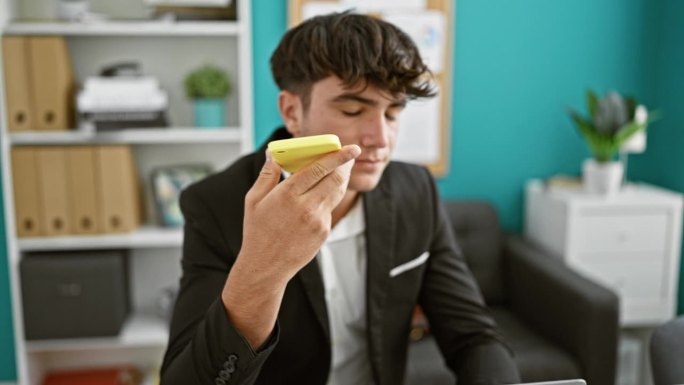 勤奋的西班牙裔年轻人在商业世界中蒸蒸日上，在办公室通过智能手机发送重要的语音信息