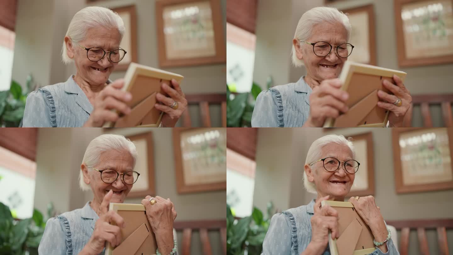 快乐的亚洲老祖母手里拿着家庭照片，在想念生命的时刻和记忆中拥抱。老年人老年生活方式理念