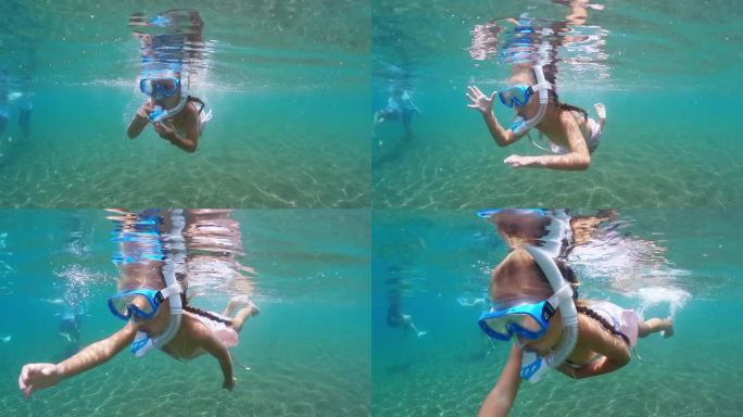女婴戴着面罩和通气管在海里游泳