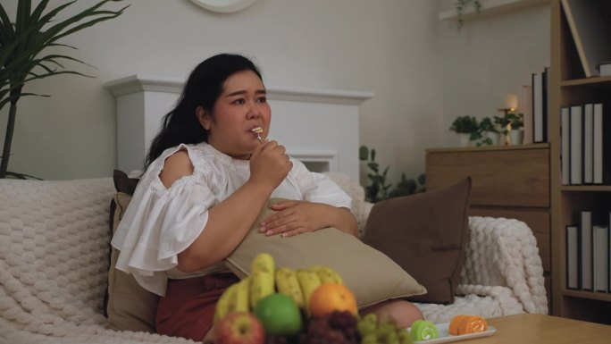 亚洲身材高大的女人一边看电视剧，一边吃着不健康的生活理念。