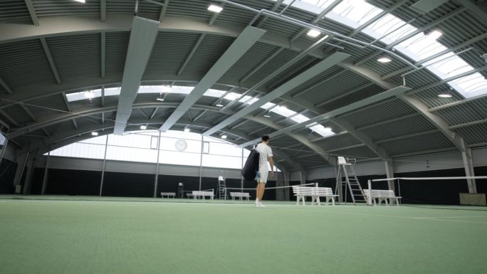 男子网球运动员走进室内网球场
