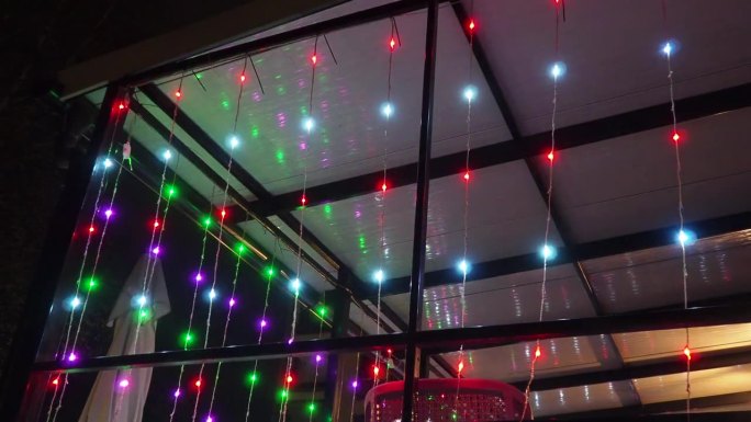 燃烧的花环。五颜六色的灯泡照亮了露台或阳台。新年的圣诞之夜。街道照明。建筑装饰。晚上咖啡馆里漂亮可爱