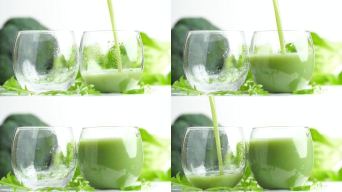在绿色蔬菜的背景下，把绿色奶昔倒进两个杯子里，旋转，慢动作。概念排毒饮料或绿色奶昔准备。