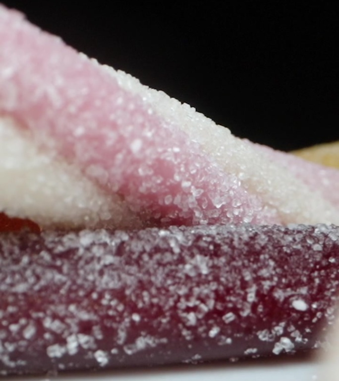 不同形状和口味的软糖落在桌子上，糖在慢动作中洒得到处都是。多莉滑块极端特写。