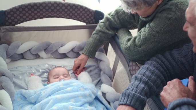 婴儿床，睡觉和祖父母带着孩子在家里建立联系，关系和照顾孩子。家庭，卧室和老年夫妇与婴儿，新生儿和儿童