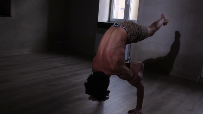 一个赤裸上身的年轻人正在瑜伽房里做瑜伽