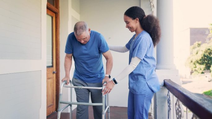 老人、男子和护士带助行器，帮助和支持活动，在阳台上进行物理治疗或康复。老年人，个人和护理人员或专业人