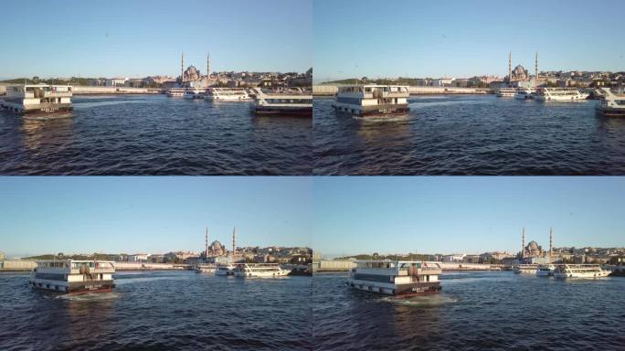 傍晚，电影般的慢镜头，从伊斯坦布尔金角湾的渡船上俯瞰埃米诺努。这张照片展示了移动的渡轮、城市景观和新