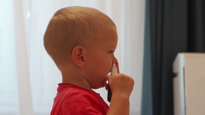感冒流鼻涕的学步儿童使用鼻喷雾剂将溶液喷在鼻子里