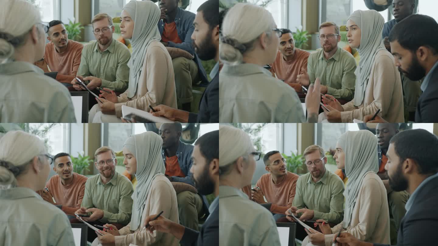 成功的穆斯林妇女在现代联合办公办公室与不同群体的同事交谈