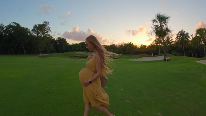 在这个令人着迷的慢动作视频中，一个孕妇优雅地走在充满活力的绿色田野上，被美丽日落的迷人色调照亮。宁静