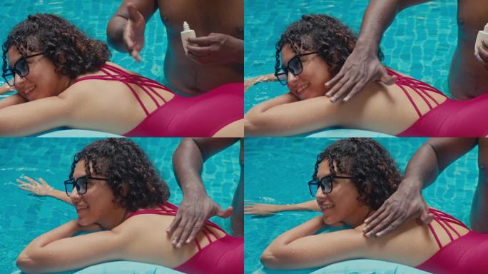 男子在酒店游泳池给女友的后背擦防晒霜
