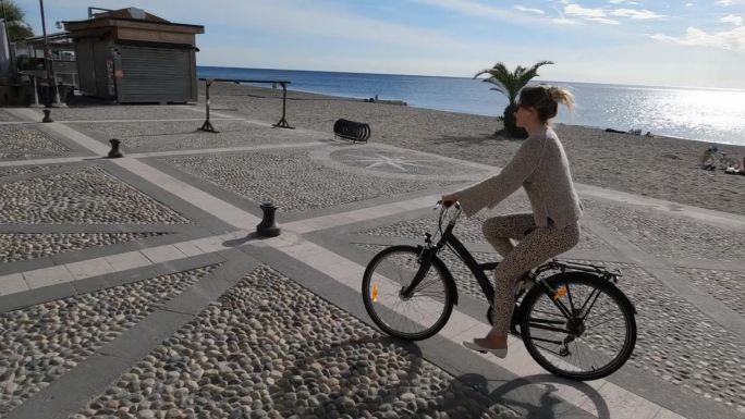 年轻女子沿着海滨步道骑自行车