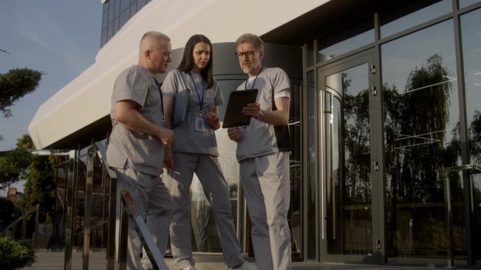 医务人员站在户外，谈论工作，使用数码平板电脑