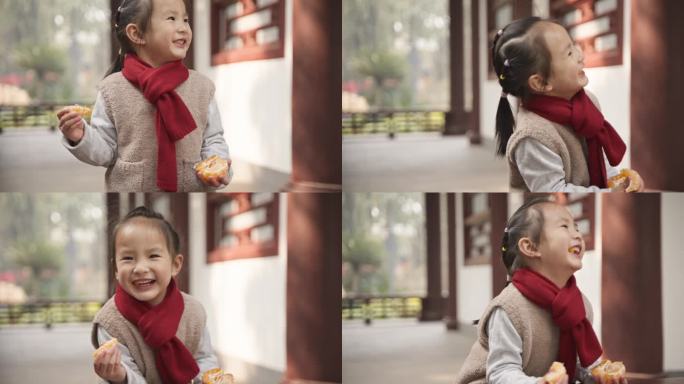 可爱小女孩围着红围巾在公园里玩耍吃橘子