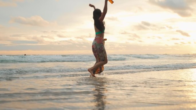 年轻女性在沙滩上尽情起舞，是度假、旅游、休闲的概念。