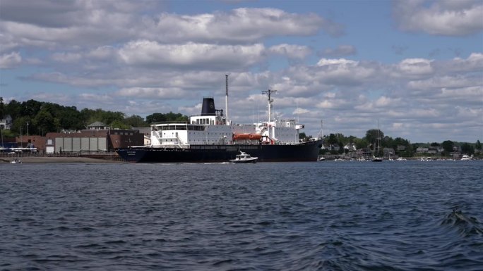 缅因州的一艘远洋船停靠在码头上，小船在原地打转