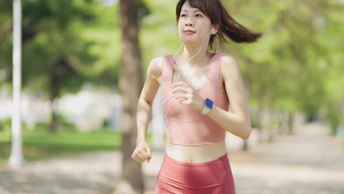 在公园里，一名亚洲女性一边用智能设备监测自己的身体数据，一边进行体育活动。