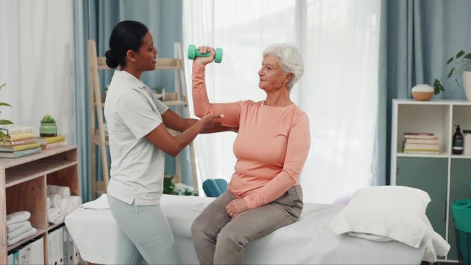老年妇女，进行理疗和哑铃锻炼，进行健康评估、体检和检查病情进展。物理治疗师咨询病人的支持，康复或愈合