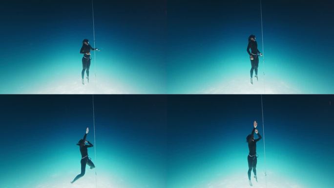 自由潜水员在绳子上锻炼。一名女子自由潜水者在开阔的海面上沿着绳索训练，然后下潜到深海