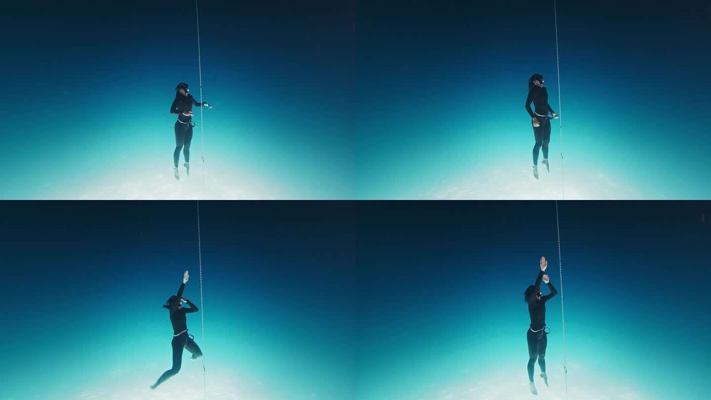 自由潜水员在绳子上锻炼。一名女子自由潜水者在开阔的海面上沿着绳索训练，然后下潜到深海