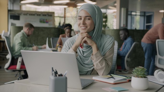 戴着头巾坐在办公桌旁的穆斯林女职员的慢动作肖像