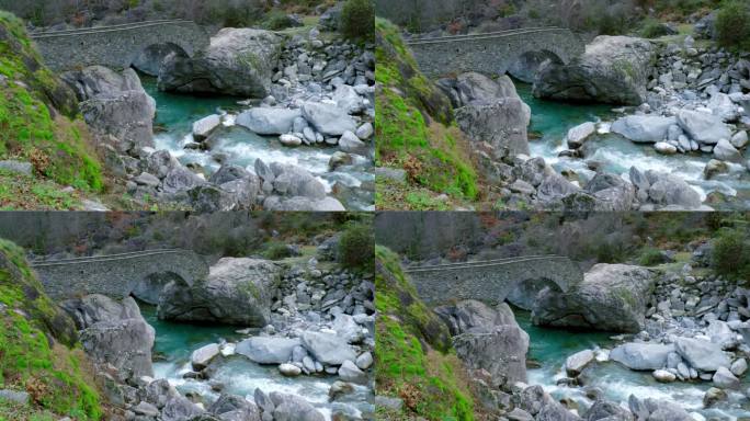 无人机从底部缓慢上升，在它的框架中显示了一座桥，流动的冰川水，以及瑞士卡弗尼奥村马吉亚河沿岸的岩石。