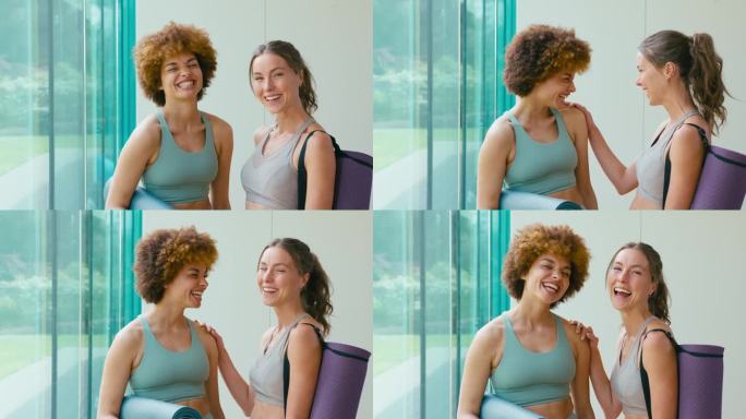 两个微笑的女人穿着运动服在健身房或瑜伽馆拿着运动垫的肖像