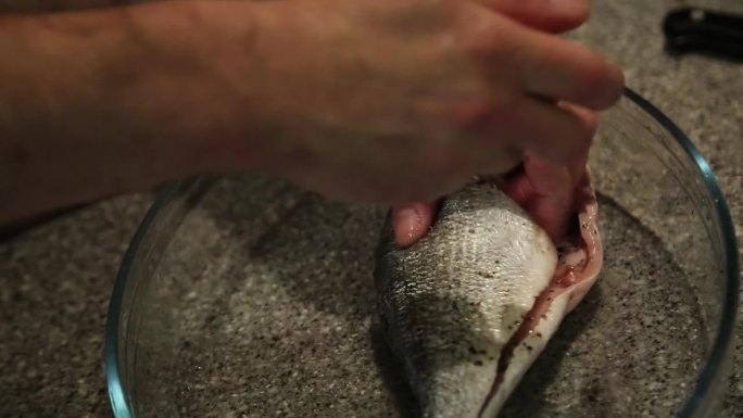 一名男子用盐和胡椒给鱼调味，烹饪的镜头